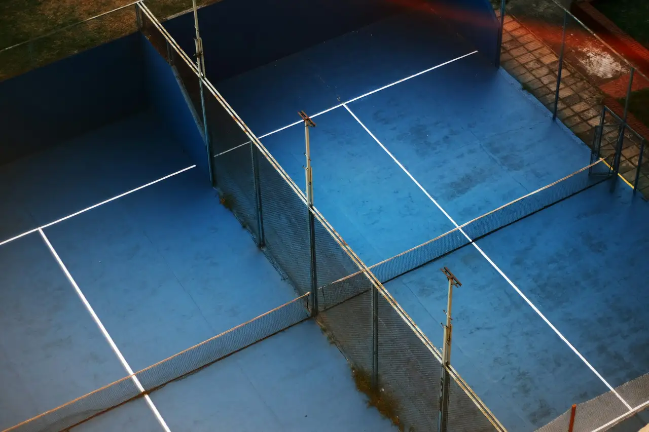 Twee lege padelbanen van bovenaf gezien, in laag avondlicht