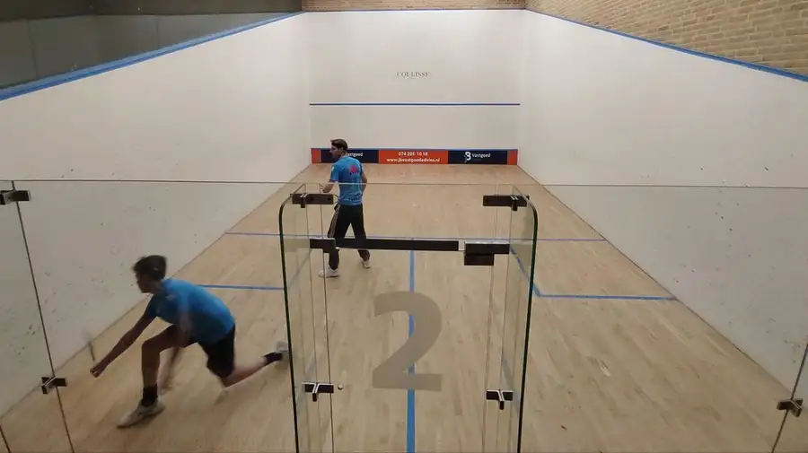Twee spelers op een squashbaan met glazen achterwand bij Racket & Fit Center in Borne